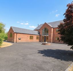 A house with a large driveway and surrounding trees at Hazeldene near Harvington