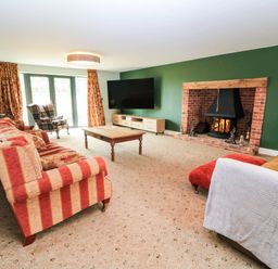 A living room with a fireplace and a television at Hazeldene near Harvington