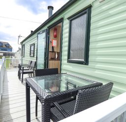 An outdoor area with chairs and a table at The Seafront Cosy Caravan in Ingoldmells