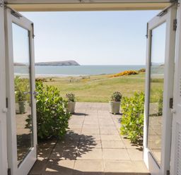 A view from an open door showcasing the sea and greenery at The Bolthole in Newport