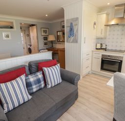 A living room with a sofa and kitchen area at The Bolthole in Newport