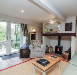 A living room with an armchair, sofa, and fireplace at The Bothy at Lewis Cottage in Spreyton