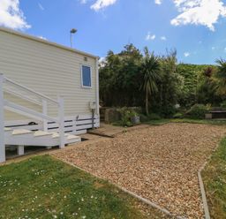 A garden with steps leading to a mobile home at Swanny View in Swanage