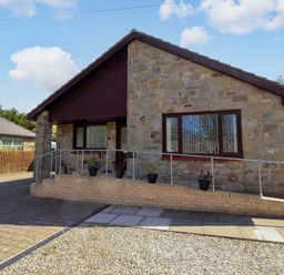 A house with stone exterior and driveway at Willow cottage in Seahouses