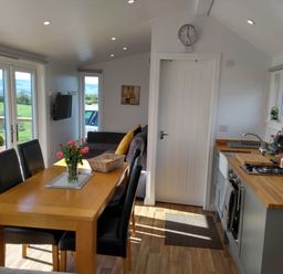 A kitchen with dining table and sofas at Cleeves Cabins 2, Arran Luxury Lodge with hot tub St. John's Town Of Dalry