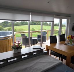 A living room with a dining table and hot tub at Cleeves Cabins 2, Arran Luxury Lodge with hot tub St. John's Town Of Dalry