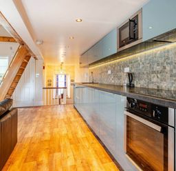 A kitchen with modern appliances and a wooden staircase at Sedbergh Penthouse - KingBed - Tv - Wifi Sedbergh