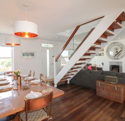 A dining room with a table set for dinner and a staircase at Lorrell in Salcombe