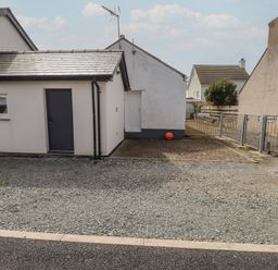An exterior view of a house with a gravel area and a ball at Kiloran Rhosneigr