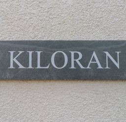 A nameplate with Kiloran displayed on a textured wall
