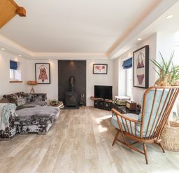 A living room with a sofa, television, and armchair at Kiloran in Rhosneigr