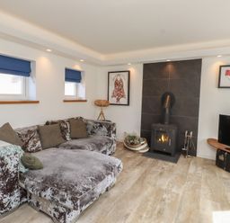 A living room with a sofa and fireplace at Kiloran in Rhosneigr