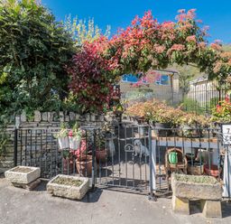An outdoor entrance with plants and a small dog at 7 The Cedars in Wotton-Under-Edge