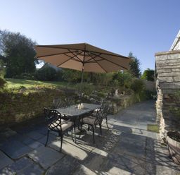 A garden with a table and chairs under an umbrella at Mays Cottage in Wadebridge
