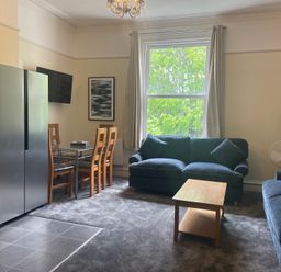 A living room with a sofa and dining area at Apartment 5 in Torquay