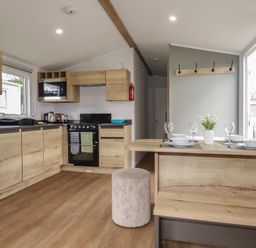 A kitchen with appliances and dining area at Shamrocks Cove Caravan