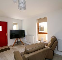 A living room with a television and a red door at The Mews @ Suskar in Laragh, County Wicklow