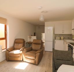 A living room with recliner chairs and a kitchen area at The Mews @ Suskar Laragh, County Wicklow