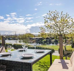 An outdoor dining setup with table and chairs overlooking a lake at Borwick Heights 17 Carnforth