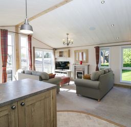 A living room with a sofa, television, and fireplace at Borwick Heights 17 in Carnforth
