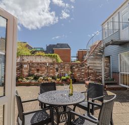 A courtyard with a table and chairs at Beck House in Weymouth