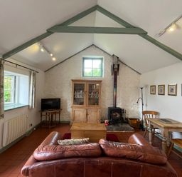 A living room with a sofa, table, and fireplace at Warbler Cottage near Cowbridge