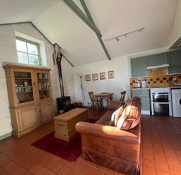 A living room with a sofa and kitchen area at Warbler Cottage near Cowbridge