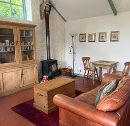 A living room with a sofa, table, and fireplace at Warbler Cottage near Cowbridge