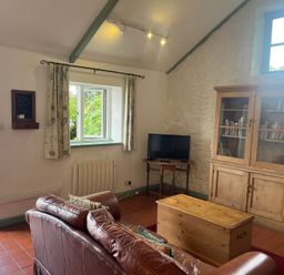 A living room with a sofa and a television at Warbler Cottage near Cowbridge