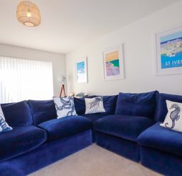 A living room with a blue sofa and artwork on the walls at Serfaus in Perranporth