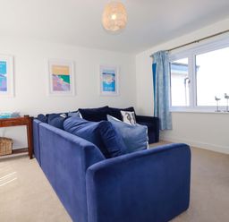 A living room with a blue sofa and a table at Serfaus in Perranporth