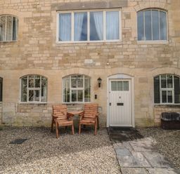 An exterior view of a building with two chairs and a door at Longfords Mill near Nailsworth