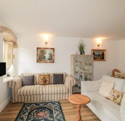 A living room with sofas, a coffee table, and a television at Longfords Mill near Nailsworth