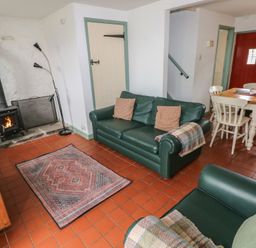 A living room with a wood stove and dining area at Swallow Cottage in Cowbridge