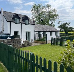 An outdoor area with a house, garden furniture and a fence at Swallow Cottage near Cowbridge