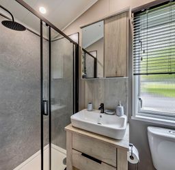A bathroom featuring a shower, sink, and toilet at Prion 1.0 Pet Llandyrnog