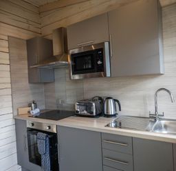 A kitchen with a stove, microwave, and sink at Pine Lodge Spa Carlton Miniott near Thirsk
