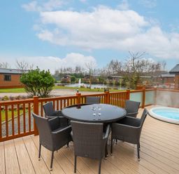 An outdoor space with a table and chairs plus a hot tub at Laurel Waterside Spa Carlton Miniott near Thirsk