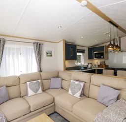 A living room with a sofa and kitchen area at 51 Calgarth Park in Troutbeck