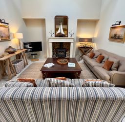 A living room with a sofa, coffee table, and lamp at The Chimney in Bamburgh