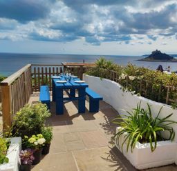 An outdoor dining area with a blue table and benches at Ty Bryn in Marazion