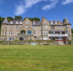 A large building with a lawn and trees at Apartment 1, Bryn Mel Manor in Menai Bridge