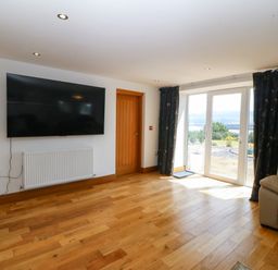 A living room with a television and a door to the outside at Apartment 1, Bryn Mel Manor Menai Bridge