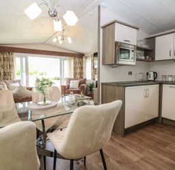 A living room with a dining area and kitchen at The Norfolk Nook 18 Castle Walk Burgh Castle