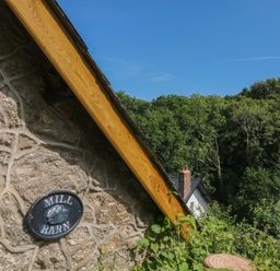 A roof with a stone wall and sign at The Mill Barn in Lustleigh