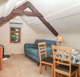 A living room with a sofa, table, and chairs at The Mill Barn in Lustleigh