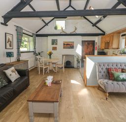 A living room with a dining area and kitchen cabinets at Daffodil Cottage in Blaencwm near Treorchy