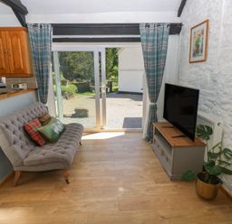 A living room with a sofa and television at Daffodil Cottage in Blaencwm near Treorchy