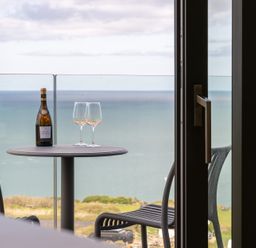 A balcony with a table and wine glasses at Clifftop House Hot Tub in St Ives