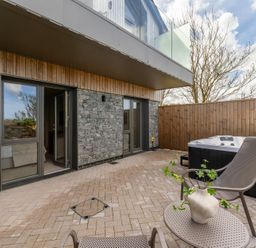 A patio with a hot tub and chairs at Clifftop House Hot Tub in St Ives